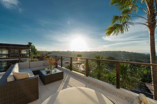 a balcony with a couch and a palm tree at Villa Jamalu by Nakula in Jimbaran