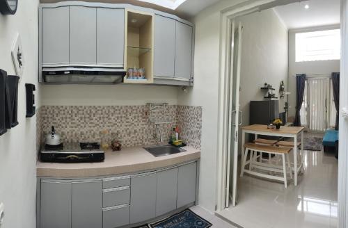 una cucina con armadi bianchi e un tavolo in una stanza di Kayana Regency F7 a Batu