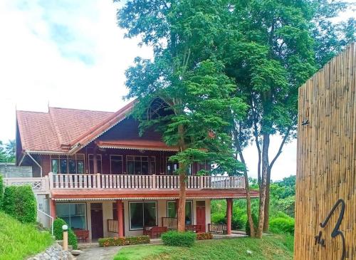ein Haus mit einem Balkon an der Seite in der Unterkunft Baanpufa Resort in Sai Yok