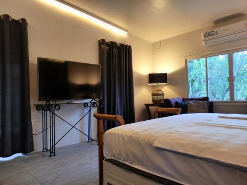 1 dormitorio con 1 cama y TV de pantalla plana en Puerto Galera Home en Balatero
