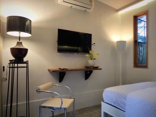 a bedroom with a bed and a flat screen tv at Puerto Galera Home in Balatero