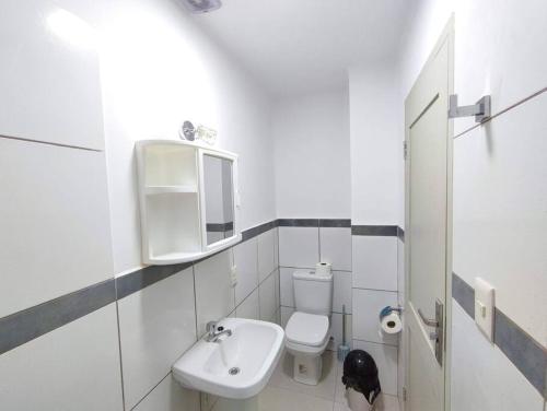 a white bathroom with a sink and a toilet at Acogedor Monoambiente en Tarija in Tarija