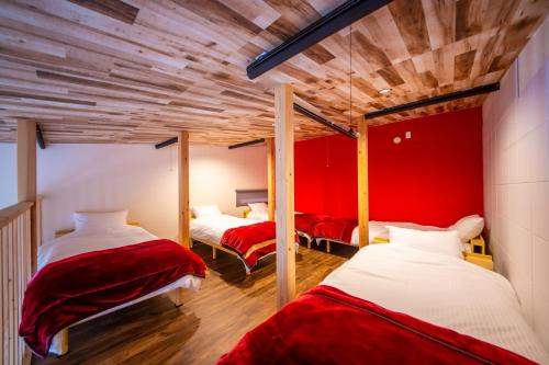 duas camas num quarto com uma parede vermelha em 千葉地域ランキング1位獲得の贅沢な貸別荘全4棟 