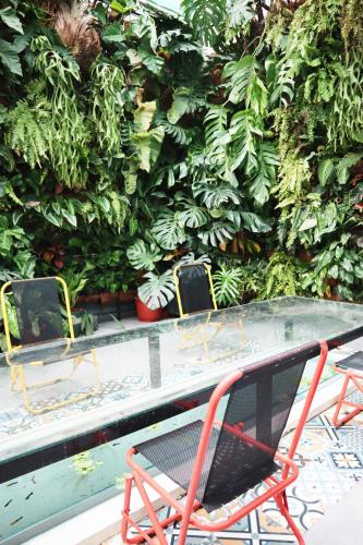 two chairs and a table in front of a green hedge at AMANGO HOSTEL in Ho Chi Minh City