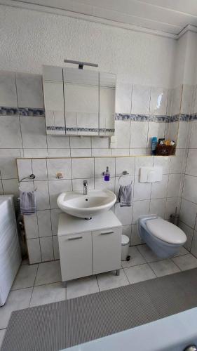 a white bathroom with a sink and a toilet at Ferienwohnung am Hofladen Hellendorf - Sächsische Schweiz in Bad Gottleuba