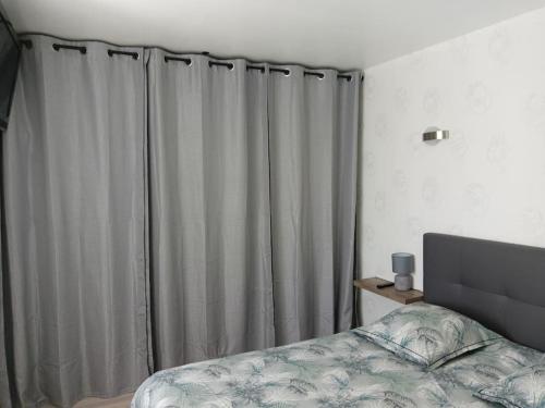 une chambre avec un lit et une fenêtre avec des rideaux dans l'établissement Appartement à 1km des plages avec 2 vélos élec, à Royan