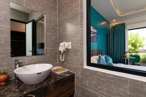 a bathroom with a sink and a mirror at Hoianese Hotel - Lip Lip Pool Villa in Hoi An