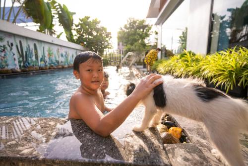 a young boy playing with a dog in a swimming pool at Hoianese Sunset Serenity Hotel in Hoi An