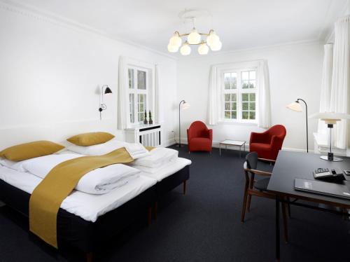 Skarrildhus Sinatur Hotel & Konference في Skarrild: غرفة نوم بسرير كبير وكرسيين احمر