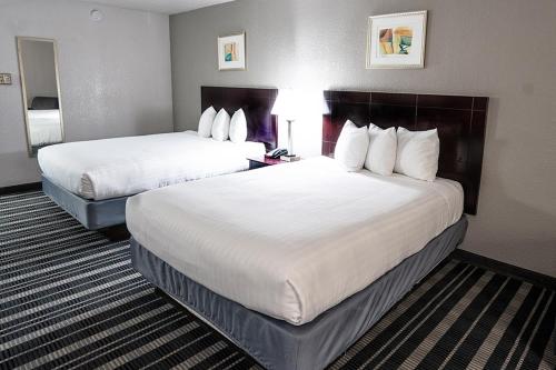 Cette chambre d'hôtel comprend 2 lits avec des draps blancs. dans l'établissement Atrium Hotel and Suites DFW Airport, à Irving