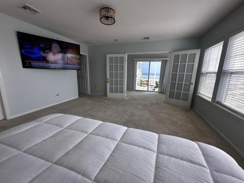 a bedroom with a large white bed and a flat screen tv at Beach House in heart of NYC in Arverne