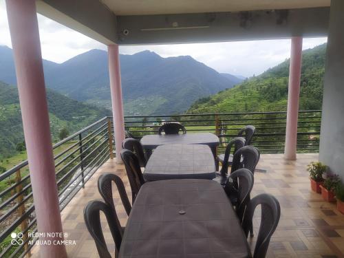 two tables on a balcony with a view of mountains at Ridhi Homestay Sari in Ukhimath