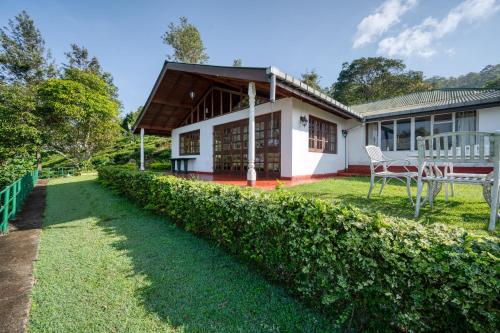 een huis met een groene heg ervoor bij Kelburne Estate in Haputale