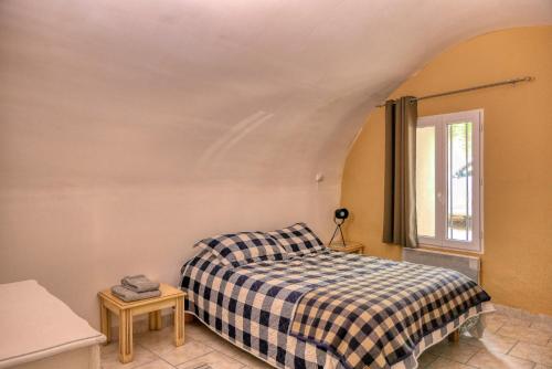 een slaapkamer met een bed met een geruite deken bij Village house of Jean in Gordes