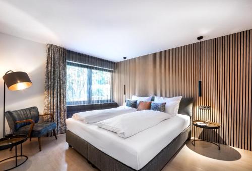 a bedroom with a large white bed and a chair at PRIMERA am See in Gaienhofen
