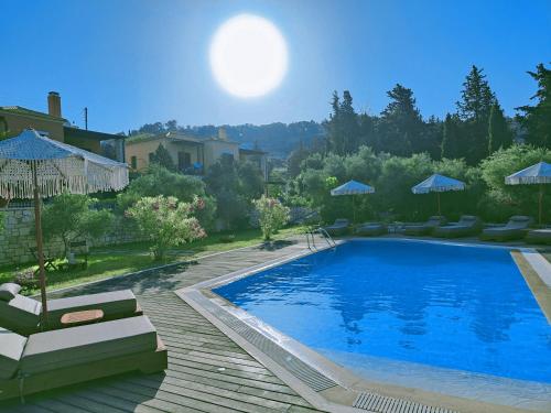 a swimming pool with chairs and umbrellas in a yard at Alkyon Villas in Syvota