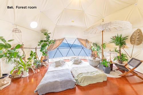 two beds in a room with potted plants at ITOSHIMA SDGs Village Chikyu MIRAI -Floating Art room or Bali Forest room- in Itoshima