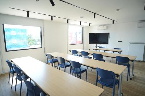 a classroom with tables and chairs and a flat screen tv at GO Hotel Ban Chang at Robinson Lifestyle Ban Chang in Ban Chang