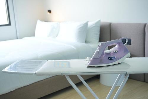 a pink iron sitting on a table next to a bed at GO Hotel Ban Chang at Robinson Lifestyle Ban Chang in Ban Chang