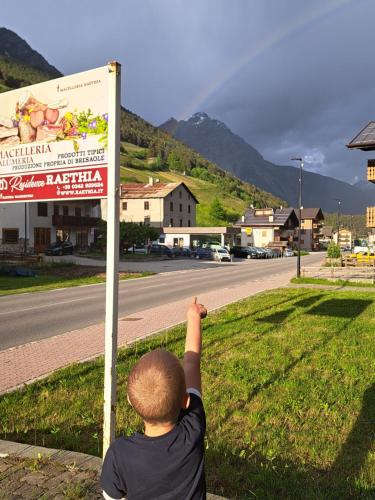 un niño está apuntando a una señal en Residence Raethia tra Bormio e Livigno, en Valdidentro