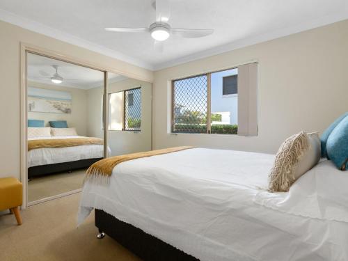 a bedroom with a large white bed and a mirror at Beachfront On Marine in Kingscliff