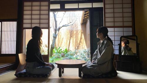 two women sitting around a table looking out of a window at Guesthouse Kioto in Kyoto