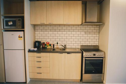 a small kitchen with a sink and a refrigerator at Liberty Apartment Hotel in Wellington
