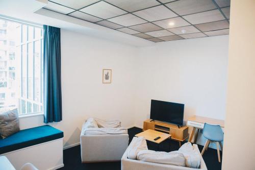 a room with a couch and a desk with a television at Liberty Apartment Hotel in Wellington