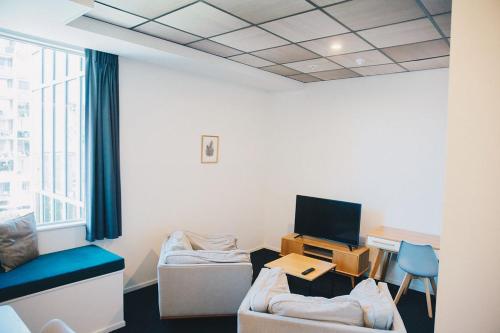Habitación con sofá y escritorio con TV. en Liberty Apartment Hotel en Wellington