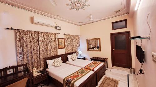 1 dormitorio con 2 camas y TV. en Sun Heritage Home, en Udaipur