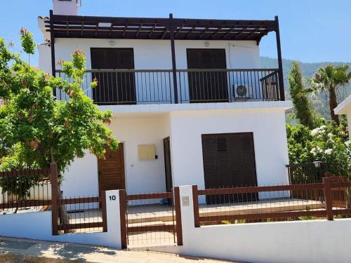 a white house with a balcony on top of it at Seaclusion Vacation Villa in Pomos