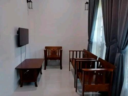 a dining room with chairs and a table and a television at Inap Kota sang rimba in Kuala Terengganu