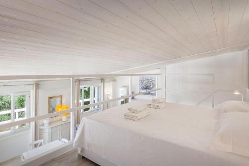 a white bedroom with a large bed and windows at Villa Roby-Loft a Torri del Benaco in Torri del Benaco