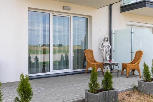 a patio with two chairs and a statue on it at Resort Kropli Bałtyku Apartments by Renters in Darłowo