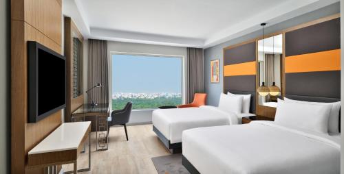 a hotel room with two beds and a television at Le Meridien Hyderabad in Hyderabad