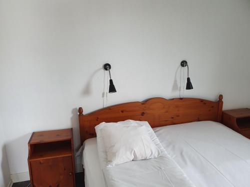 1 cama con cabecero de madera y almohada blanca en Hotell Dalsland, en Ed