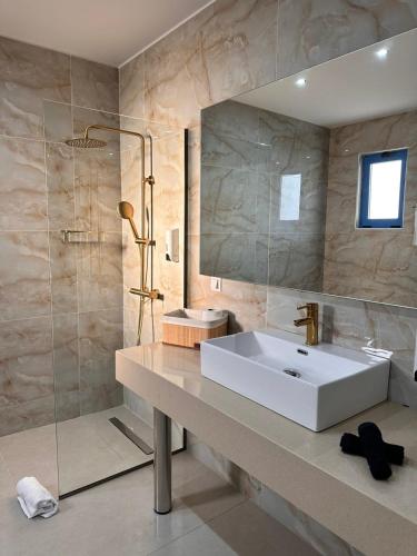 a bathroom with a white sink and a shower at Haven Beach in Faliraki