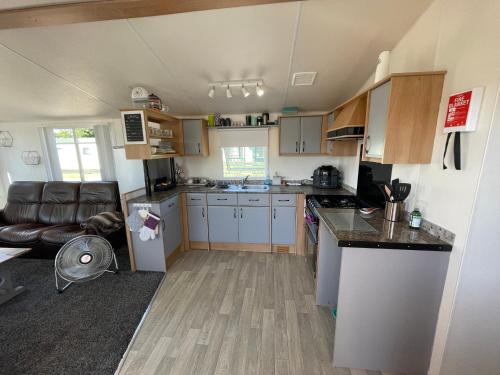 a kitchen with white cabinets and a counter top at 6 Rannoch, lovely holiday static caravan for dogs & their owners. in Forfar