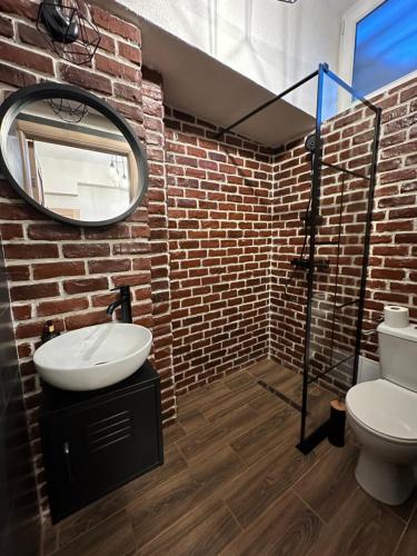 a brick walled bathroom with a sink and a mirror at Studio Zeus in Neptun