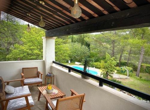 eine Terrasse mit einem Tisch und Stühlen sowie einem Pool in der Unterkunft Villa avec piscine au calme in Seillans