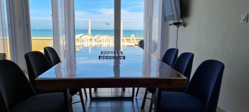 a dining room table with chairs and a view of the beach at Relais des îles Saint Marcouf in Saint-Marcouf