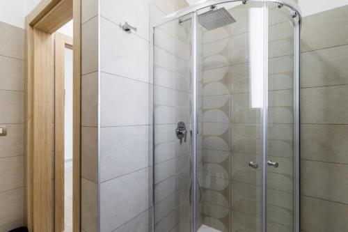 La salle de bains est pourvue d'une douche avec une porte en verre. dans l'établissement Le scuderie 5, à Galatone