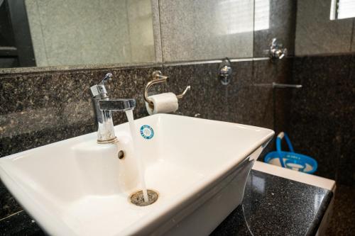 un lavandino bianco in un bagno con specchio di RONNE'S VILLA De SOL-3BHK LUXURY VILLA In Assagaon a Mapusa