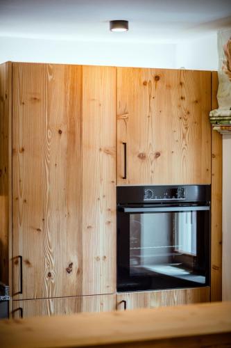 a microwave in a wooden cabinet in a kitchen at Thorbäck Gut - Apartments im Schlosserhaus in Öblarn