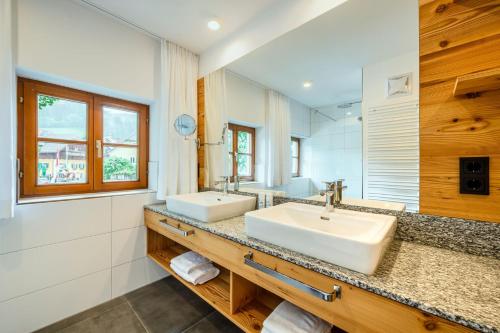 a bathroom with two sinks and a mirror at Thorbäck Gut - Apartments im Schlosserhaus in Öblarn