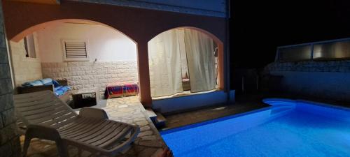 a swimming pool with a chair next to a house at Apartments Villa Bella Vista Hvar in Hvar