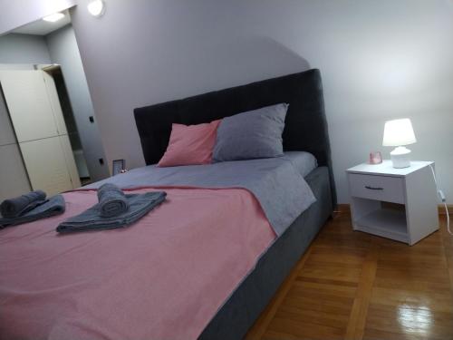 a bedroom with a large bed with pink and grey sheets at Loft apartman in Jagodina