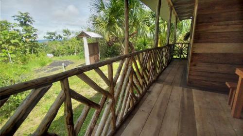 un porche de madera de una casa con vistas a un campo en Rainforest Hut, en Archidona