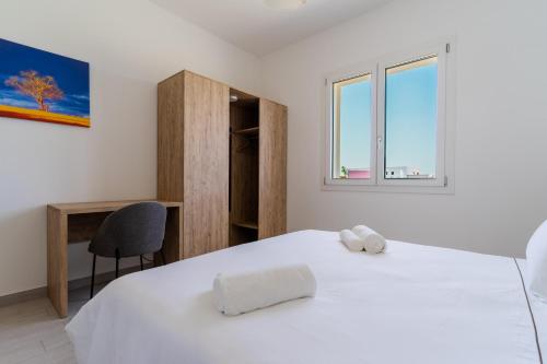1 dormitorio con 1 cama blanca con silla y ventana en Le scuderie 1, en Galatone