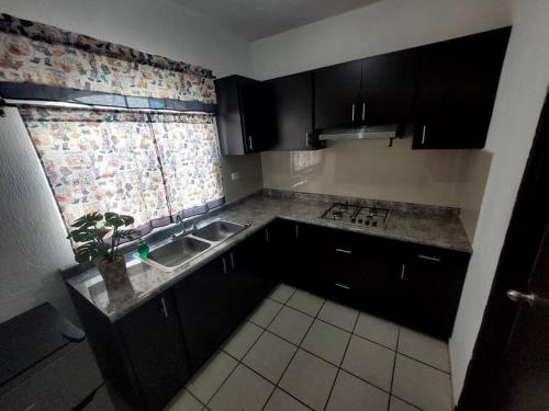 uma cozinha com armários pretos, um lavatório e uma janela em Residencia en Mazatlán em Mazatlán